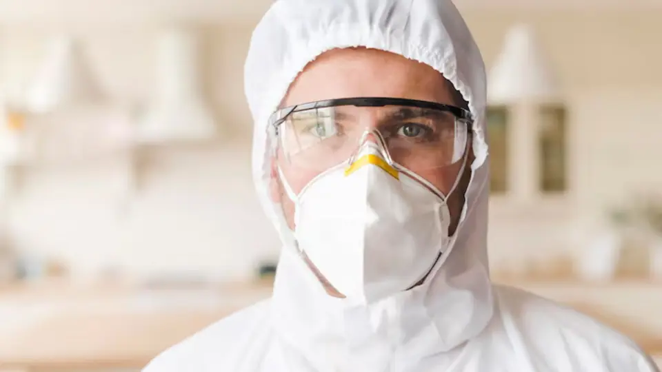 Mold remediation technician wearing a respirator and protective hood
