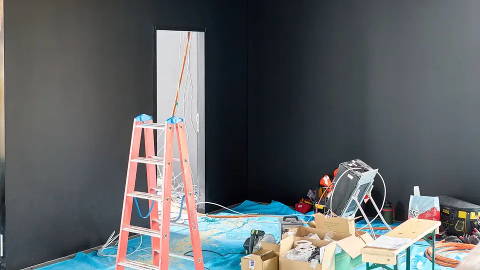 Room prepared with tarps, a ladder and drying equipment for water damage cleanup