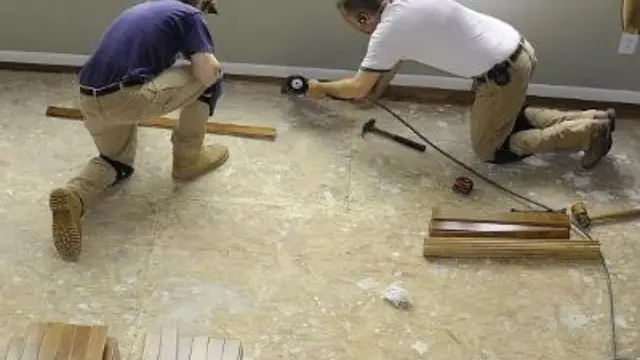 Two workers repairing a damaged floor after water damage