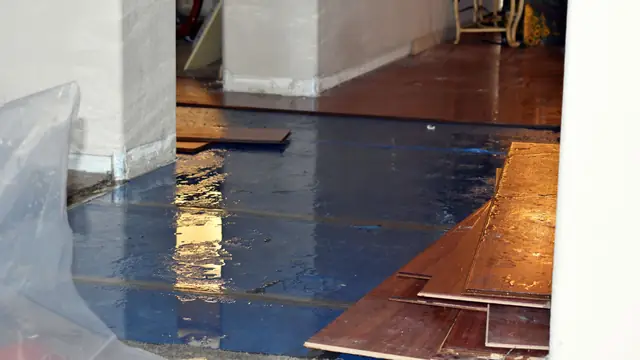 Water-damaged wood flooring lifted and covered with plastic